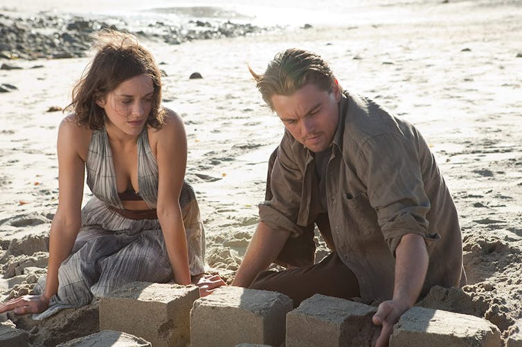 Movie still, Mal and Cobb on a beach.