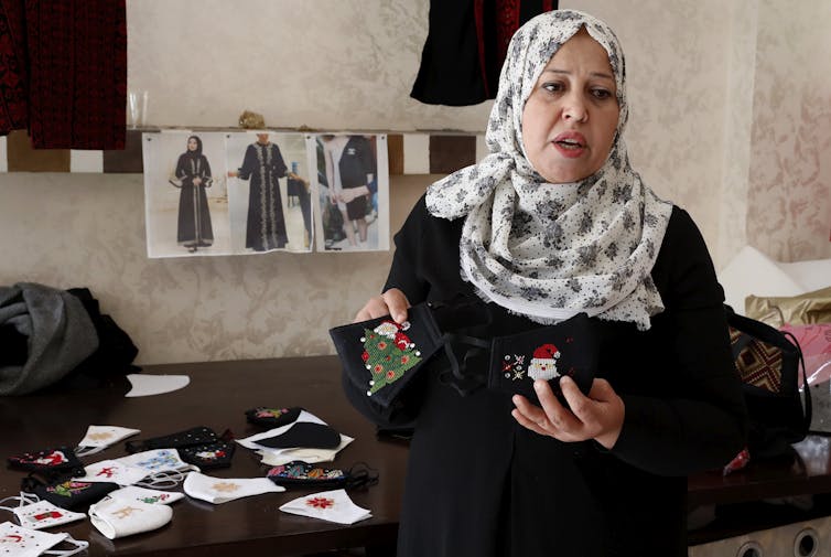 A woman holds up face masks at her sewing studio.