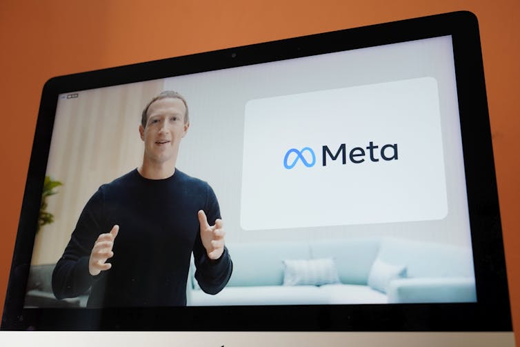 A screen showing Mark Zuckerberg and the new Meta logo