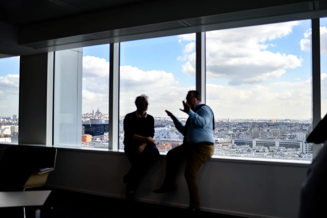 two men sitting beside window having conversation