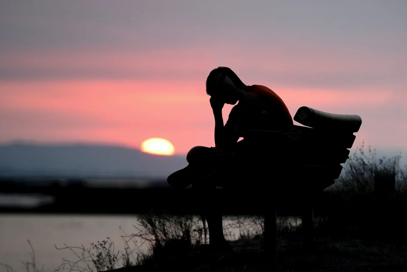 silhouette of woman sitting on bench during sunset