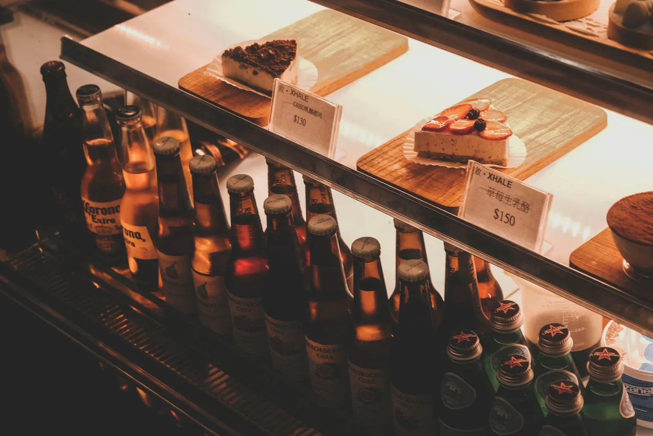displayed glass bottles under displayed desserts with price tags