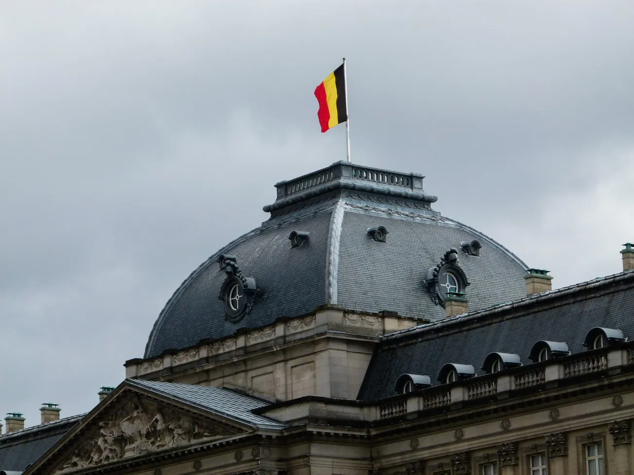 gray and white building with red, yellow, and black striped flag on roof