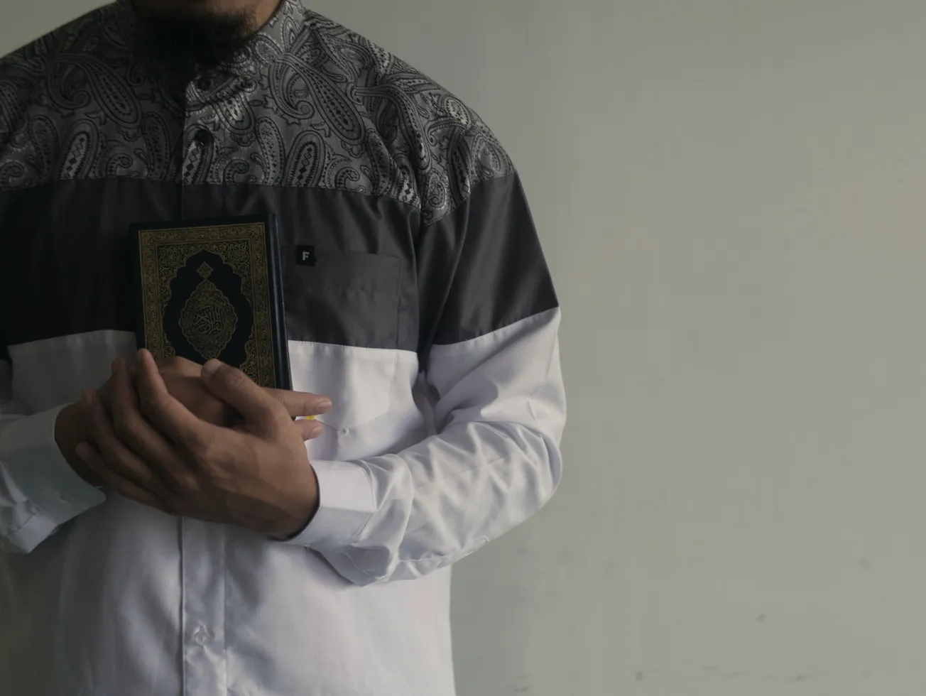 man in white dress shirt holding black and yellow book