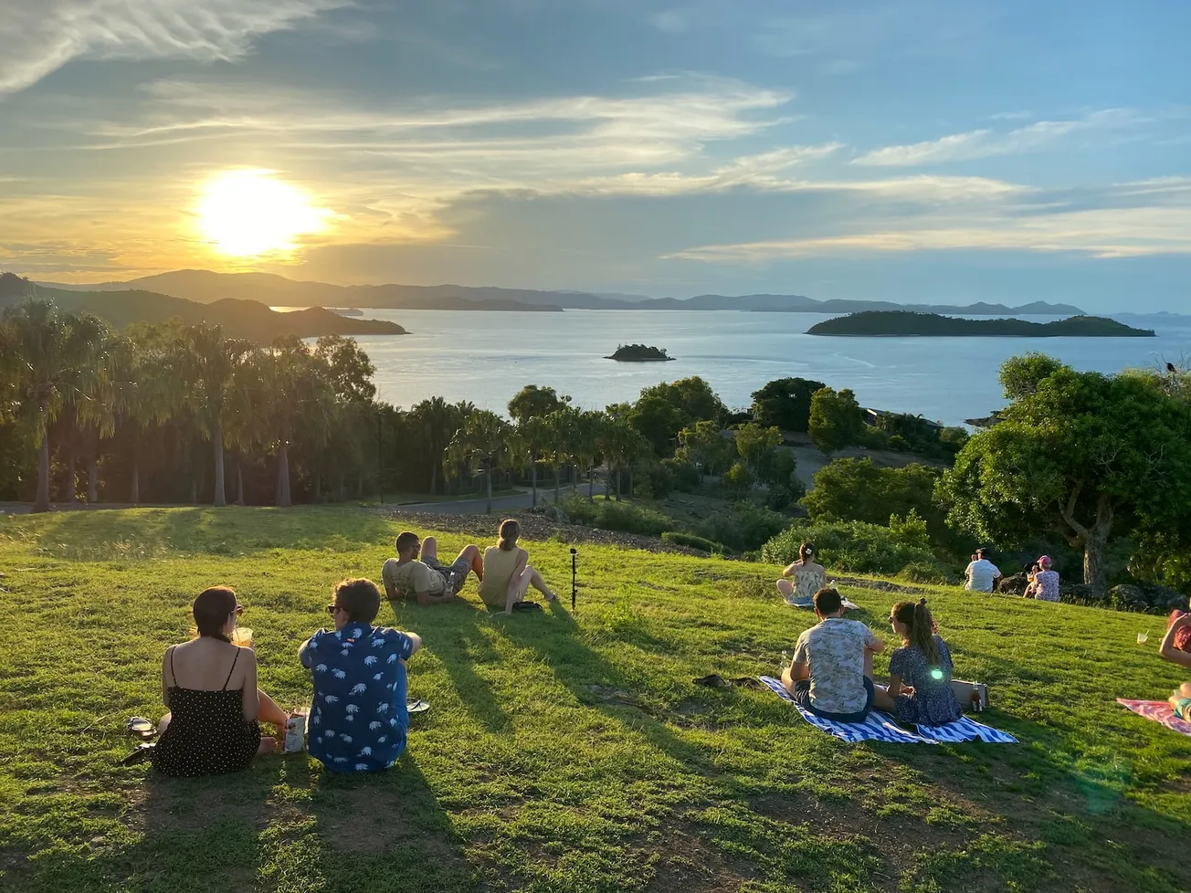 people sitting on green grass field near green trees during daytime