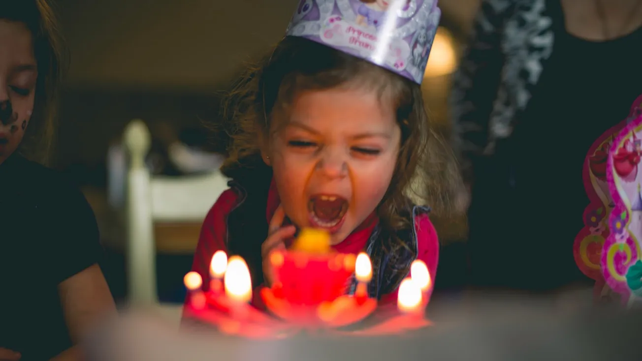 shallow focus photography of toddler blowing cake candles