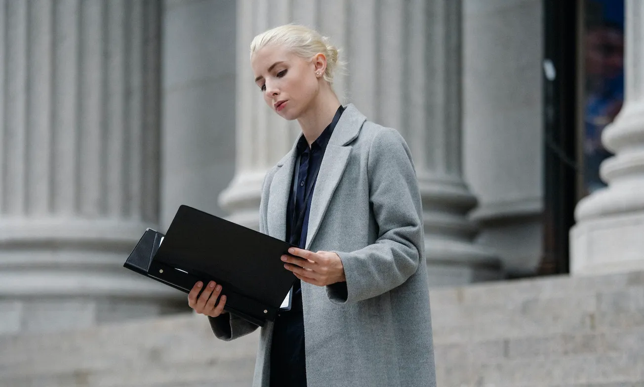 Contemplative businesswoman reading papers in folder outside building