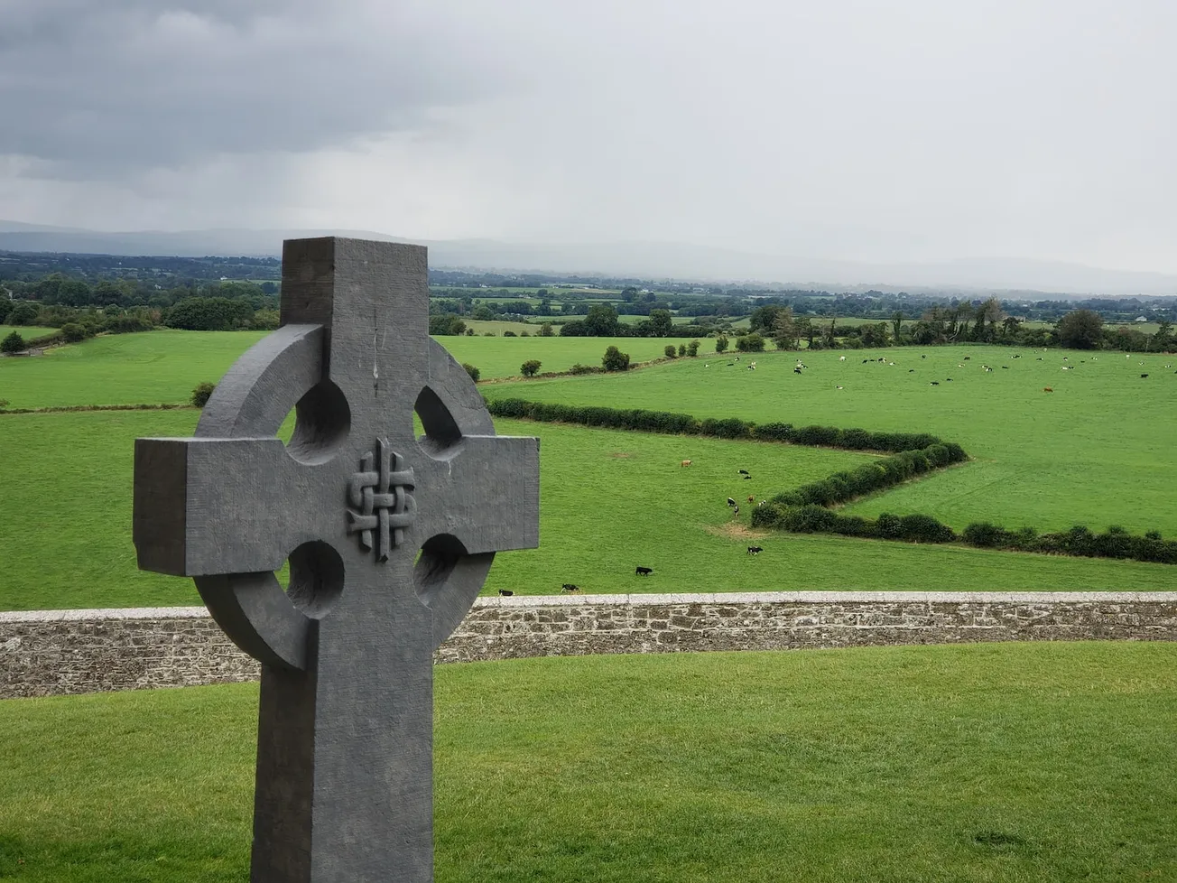 gray concrete cross on grass field during day