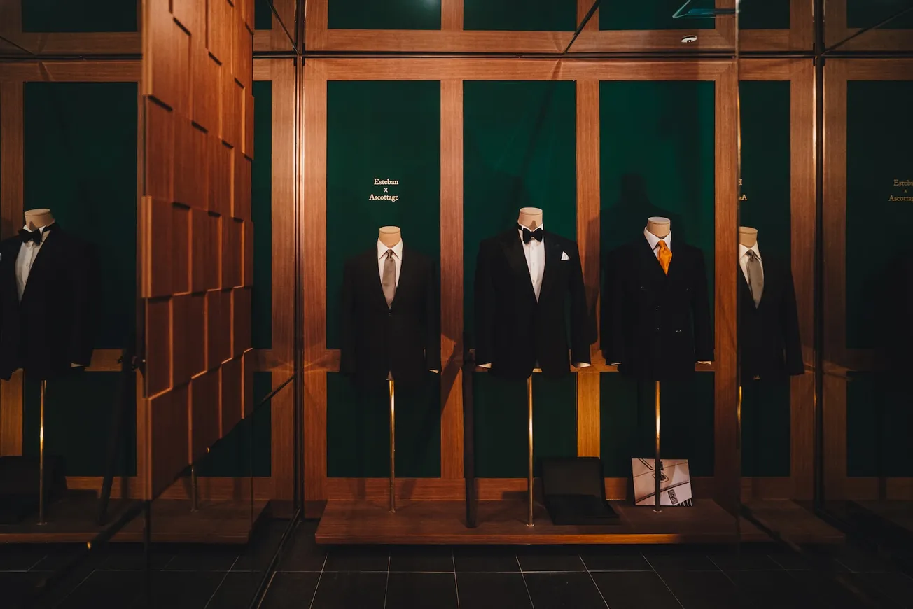 man in black suit standing near brown wooden door