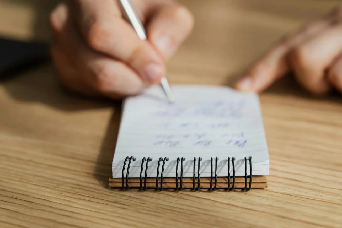 Crop man writing in notebook with pen